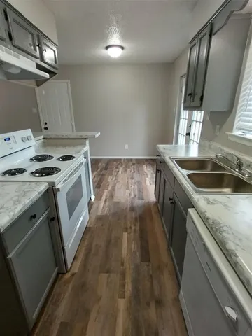 a kitchen that has a sink a stove and wooden floor