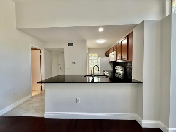 a view of a kitchen with kitchen island a sink wooden floor and a counter top space