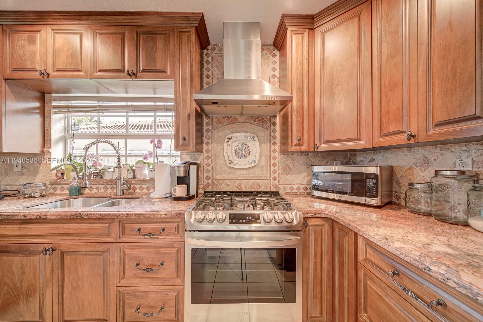 18128 Southwest 151st Avenue Miami, FL 33187 - Photo 22 of 39 a kitchen with granite countertop stainless steel appliances stove top oven and cabinets