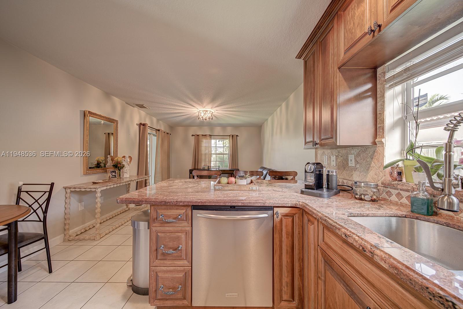 18128 Southwest 151st Avenue Miami, FL 33187 - Photo 23 of 39 a kitchen with kitchen island granite countertop a sink stove and cabinets