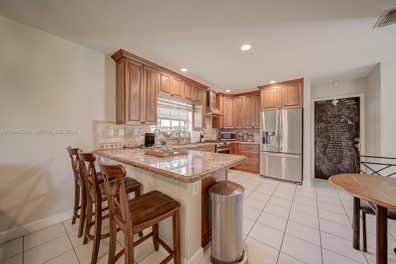 18128 Southwest 151st Avenue Miami, FL 33187 - Photo 27 of 39 a kitchen with stainless steel appliances kitchen island granite countertop a sink and a refrigerator