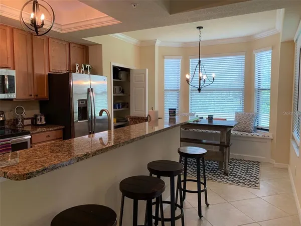 a kitchen with granite countertop a table chairs stove and refrigerator