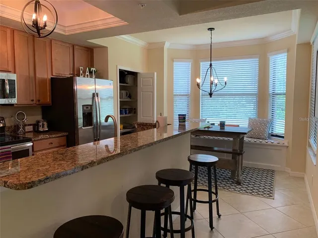 a kitchen with granite countertop a table chairs stove and refrigerator