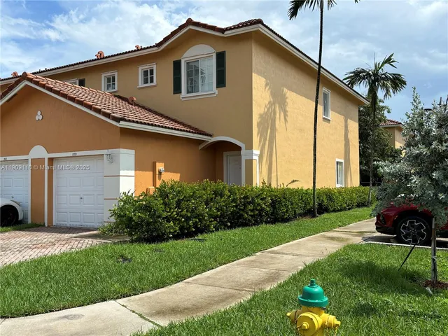 a front view of a house with a garden and plants