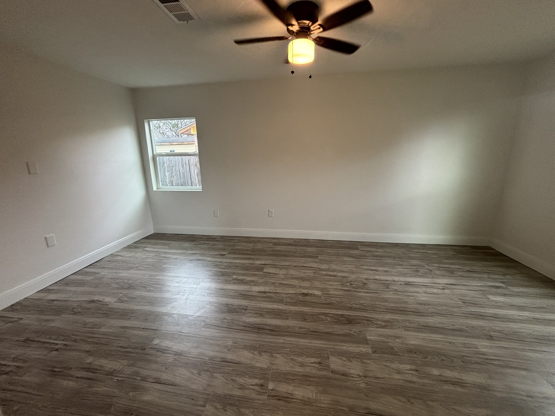9843 Ribbonwood Street Houston, TX 77078 - Photo 4 of 14 an empty room with wooden floor fan and windows