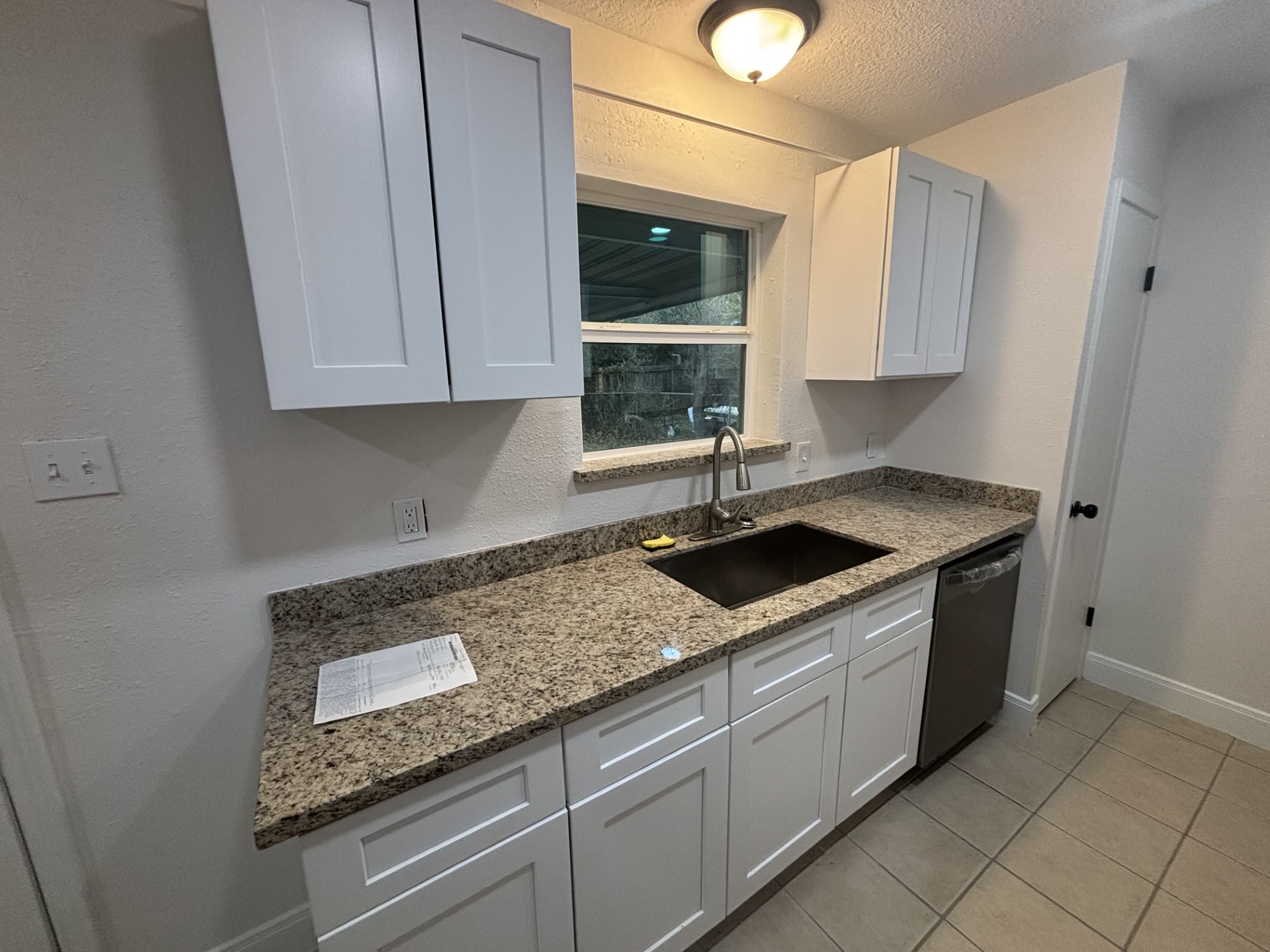 9843 Ribbonwood Street Houston, TX 77078 - Photo 7 of 14 a kitchen with granite countertop a sink stainless steel appliances white cabinets and a window