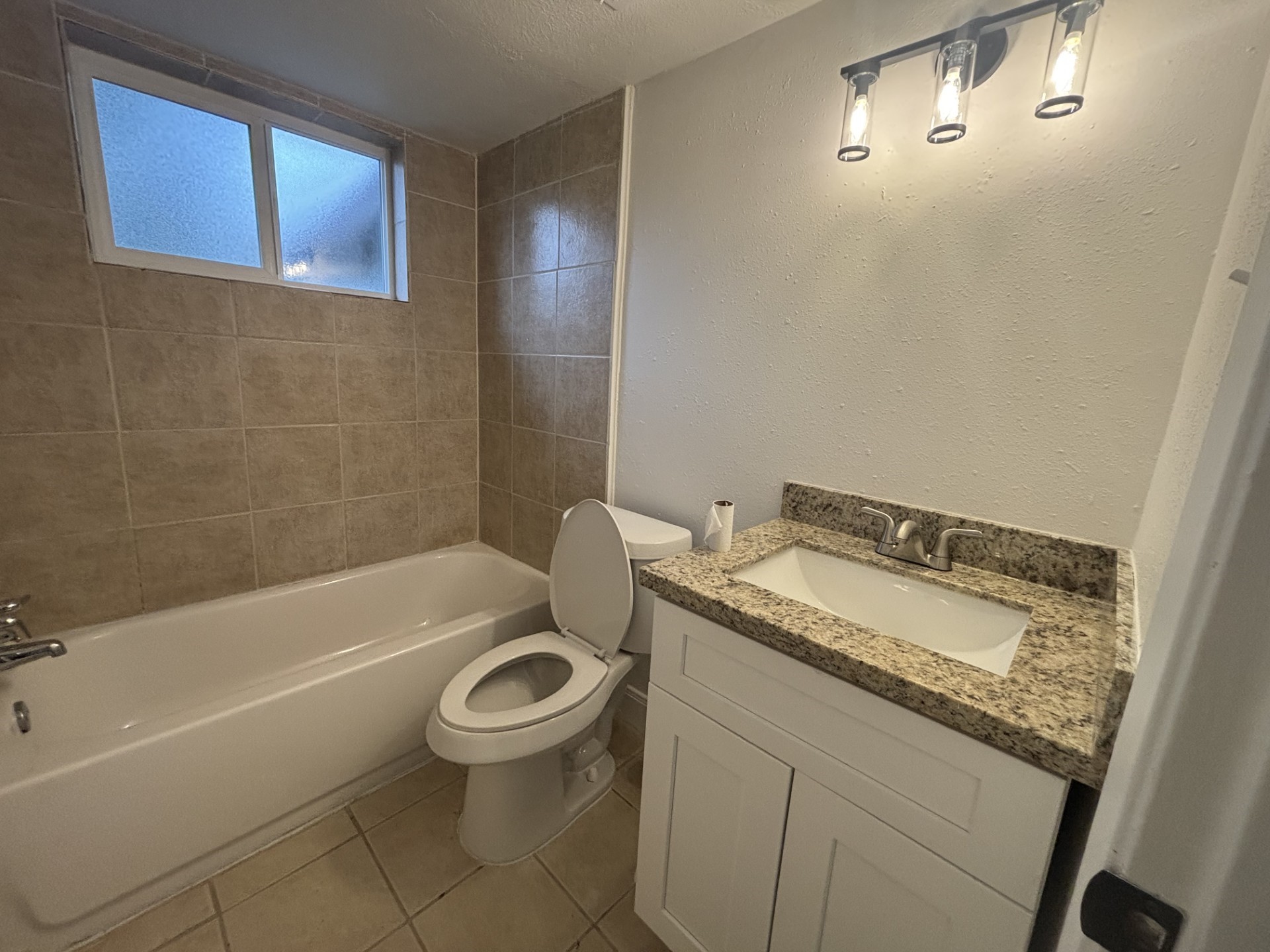 9843 Ribbonwood Street Houston, TX 77078 - Photo 9 of 14 a bathroom with a granite countertop sink a toilet and bathtub