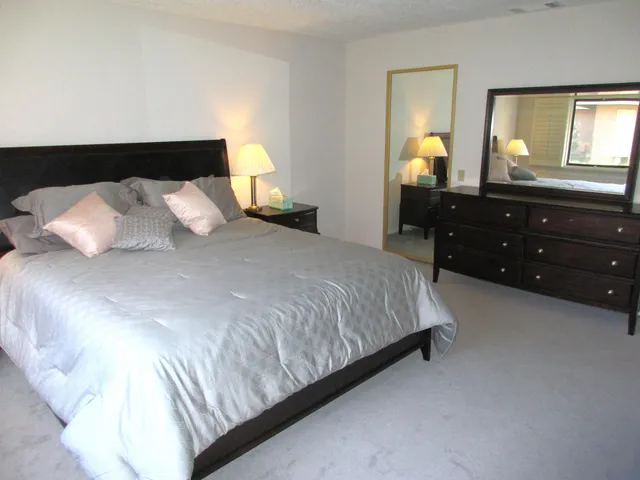 a bedroom with a bed and a mirror on dresser