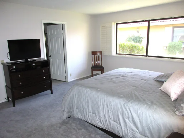 a bedroom with a bed and a flat tv screen on dresser