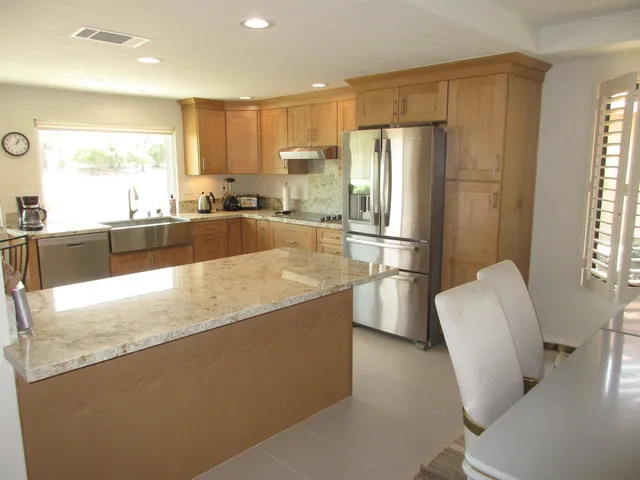 a kitchen with stainless steel appliances granite countertop a refrigerator a stove a sink a dining table and chairs