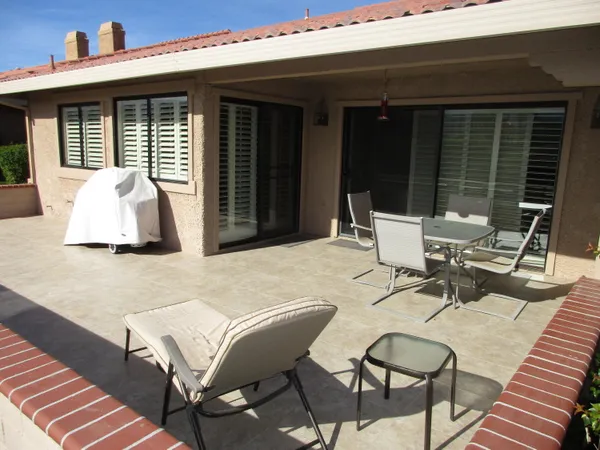a view of a patio with table and chairs with wooden floor and fence