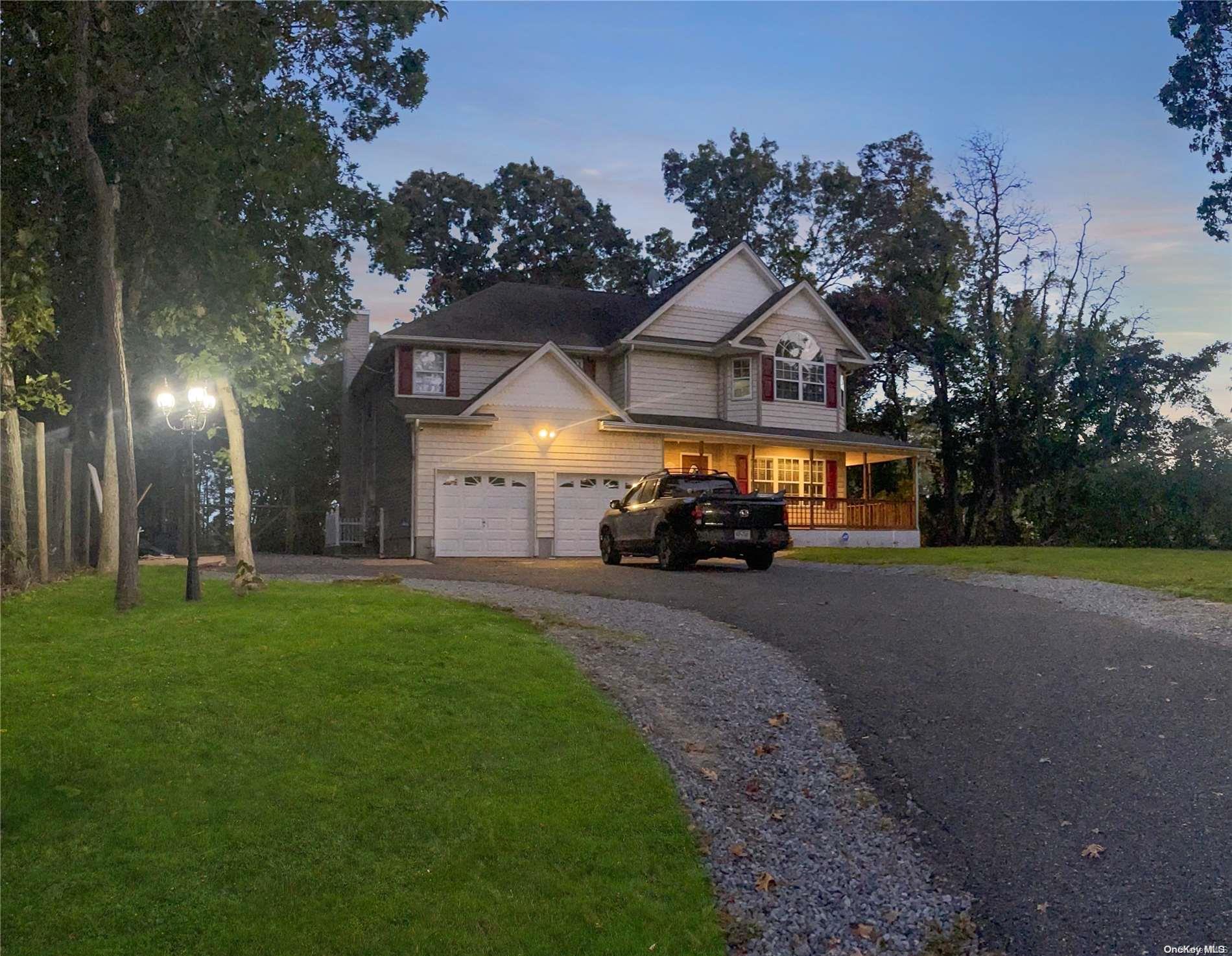 a view of house with a big yard and large trees