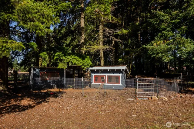 a view of a barn with wooden fence and a tree
