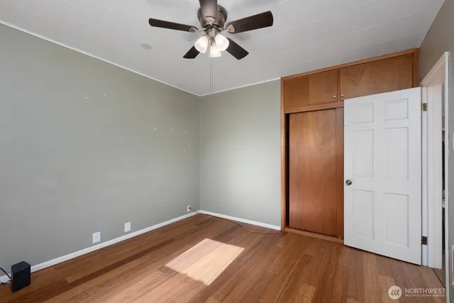an empty room with wooden floor closet and ceiling fan