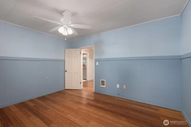 an empty room with wooden floor and fan