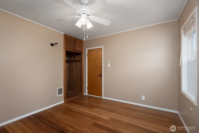 a view of an empty room with wooden floor and a window