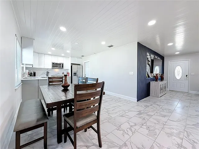 a kitchen with stainless steel appliances kitchen island granite countertop a refrigerator a stove a sink dishwasher and white cabinets with wooden floor