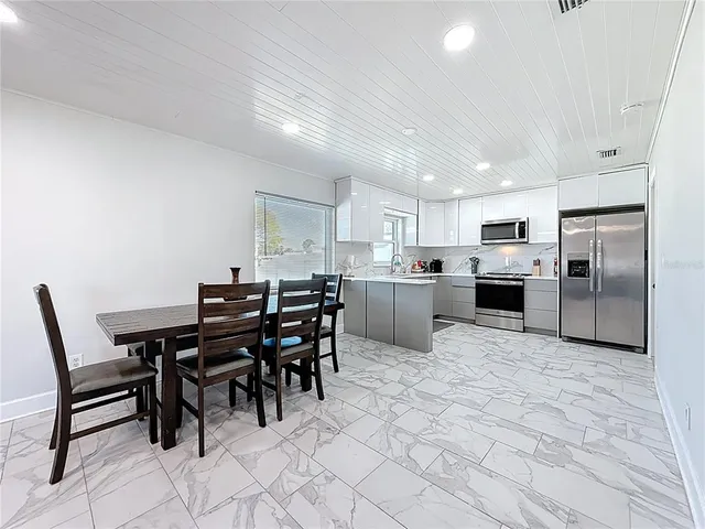 a kitchen with stainless steel appliances granite countertop white cabinets a refrigerator and a stove top oven