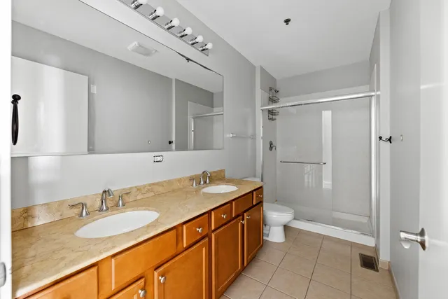 a bathroom with a granite countertop sink a mirror a toilet and shower