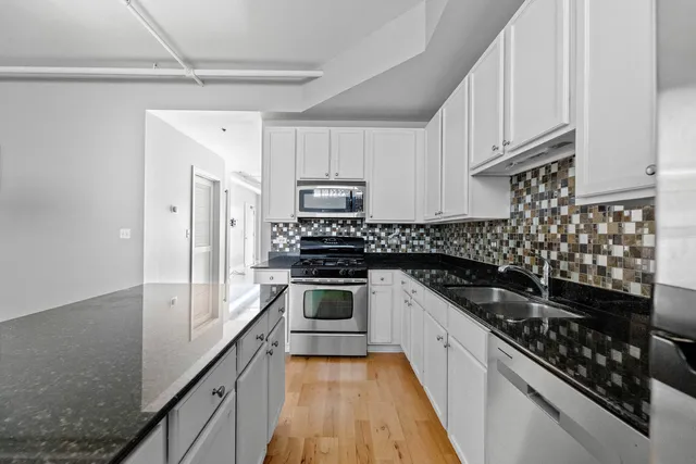 a kitchen with granite countertop a sink stove and cabinets