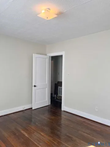 a view of an empty room with wooden floor and closet