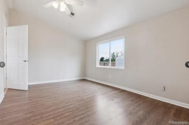 an empty room with wooden floor chandelier fan and windows