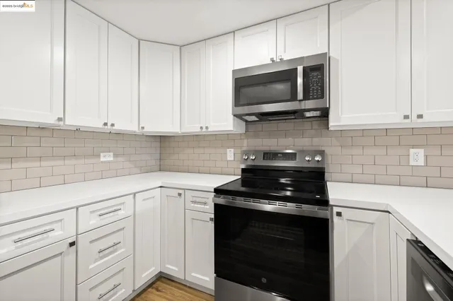 a kitchen with white cabinets and black appliances