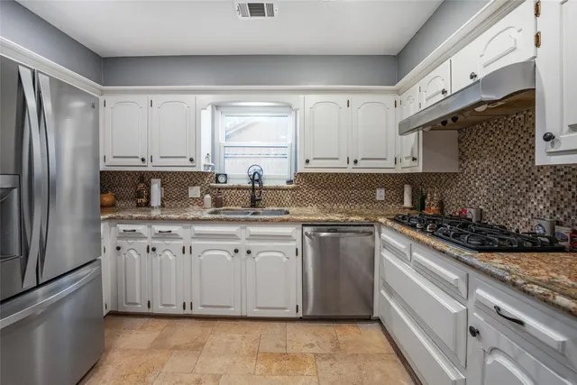 a kitchen with granite countertop a sink stainless steel appliances and cabinets