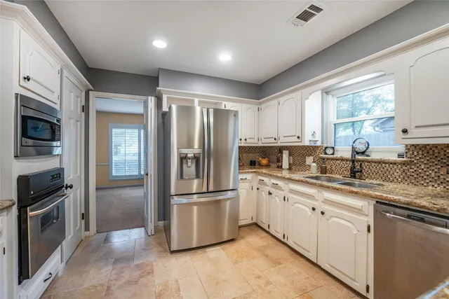 a kitchen with granite countertop stainless steel appliances a sink cabinets and a window