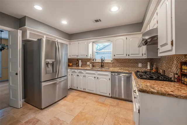 a kitchen with granite countertop stainless steel appliances a refrigerator stove top oven and sink