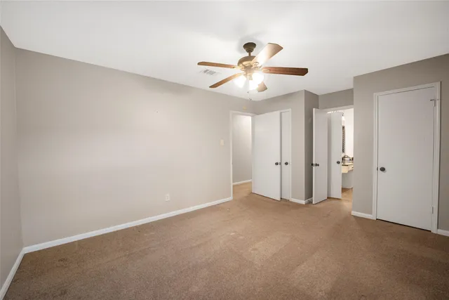 an empty room with chandelier fan and windows