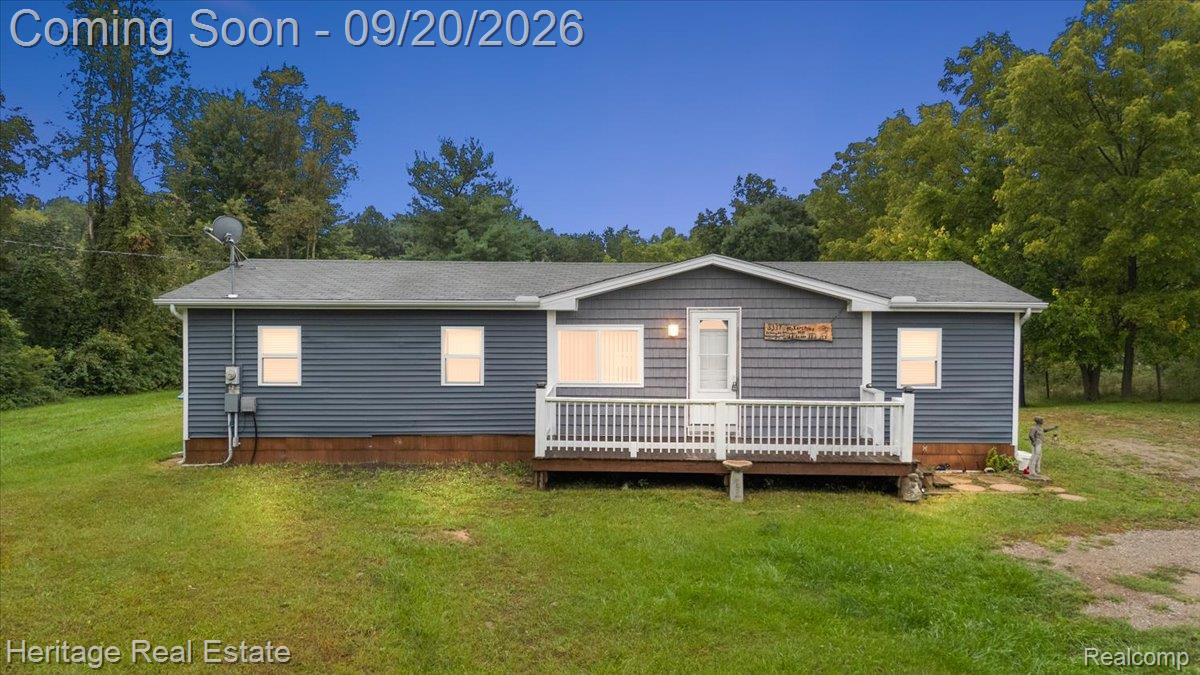 3337 Le Valley Road Columbiaville, MI 48421 - Photo 1 of 57 Exterior featuring blue horizontal siding, a covered wooden deck with white railings, and a gray shingle roof