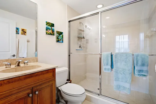 a bathroom with a granite countertop shower sink vanity mirror and toilet