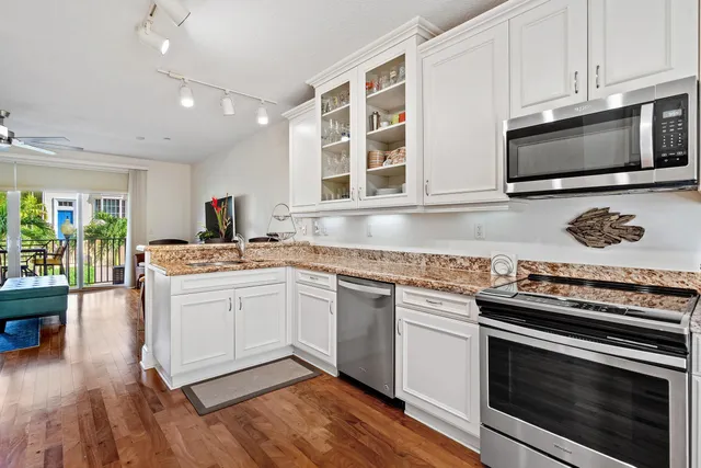 a kitchen with stainless steel appliances white cabinets granite counter tops and a hard wood floors