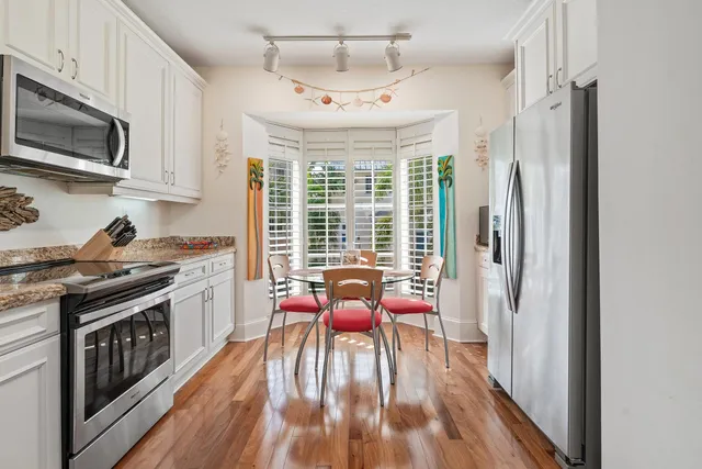 a kitchen with stainless steel appliances granite countertop a stove top oven a sink dishwasher a dining table and chairs with wooden floor