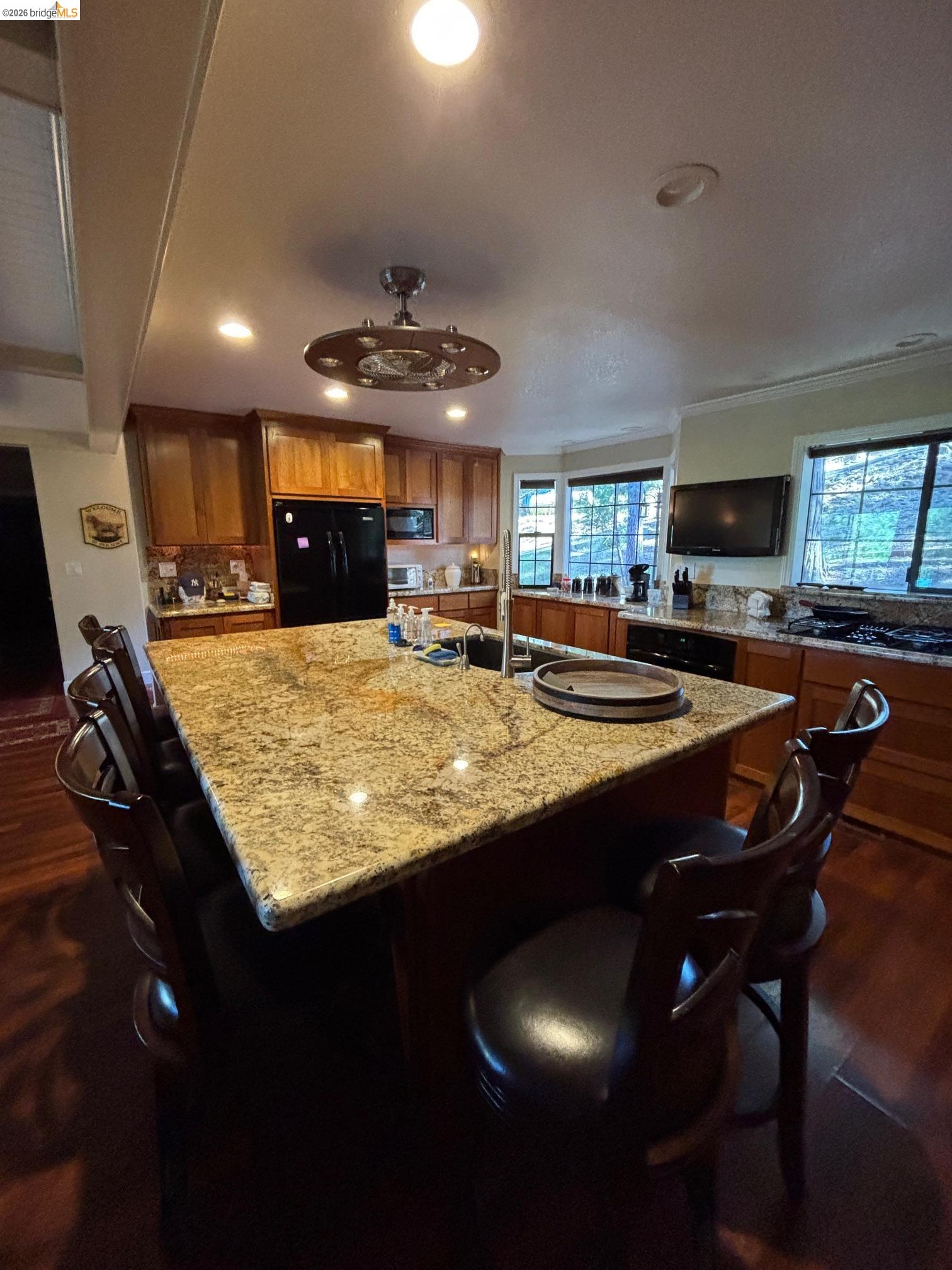 a kitchen with kitchen island granite countertop wooden cabinets a counter top space a sink and appliances
