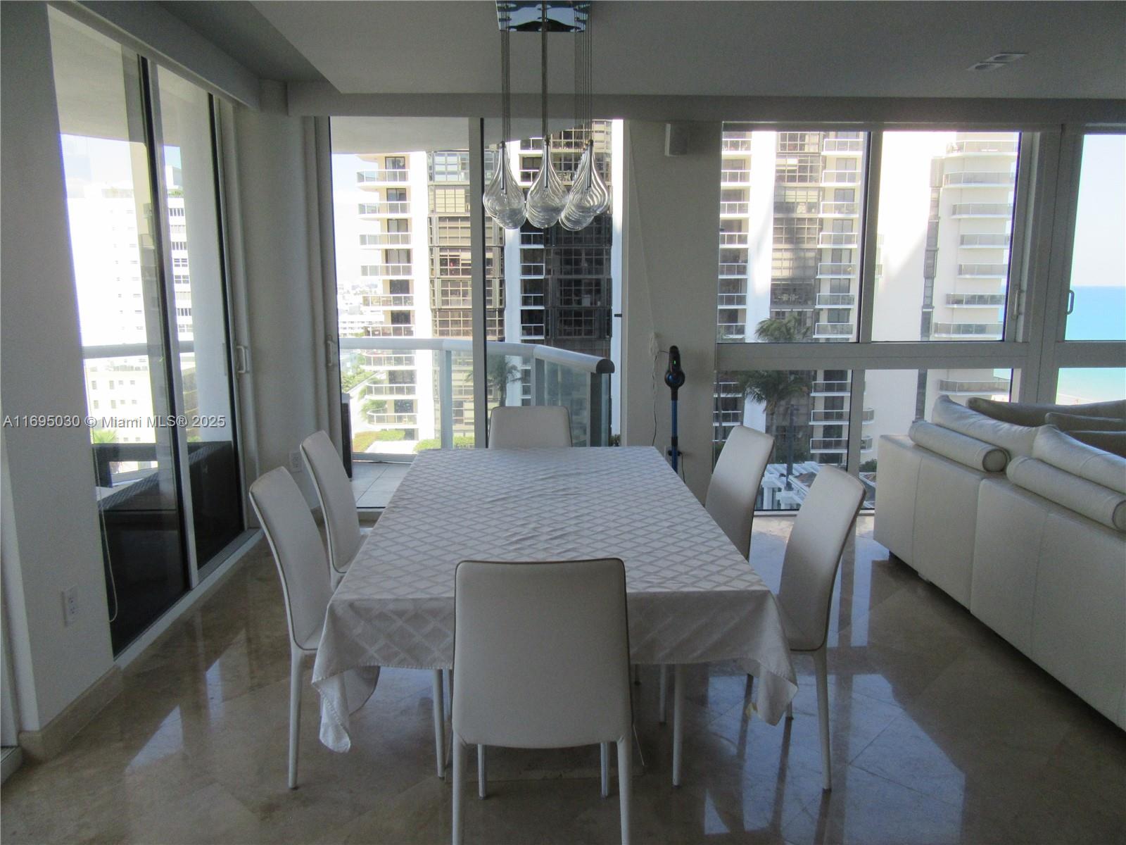 6365 Collins Avenue, Unit 1008 Miami Beach, FL 33141 - Photo 13 of 49 a view of a dining room with furniture large windows and wooden floor