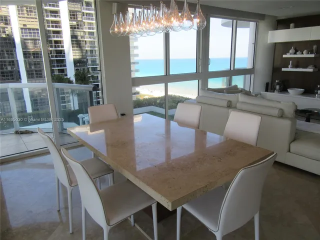 a kitchen with stainless steel appliances granite countertop a dining table chairs and a refrigerator