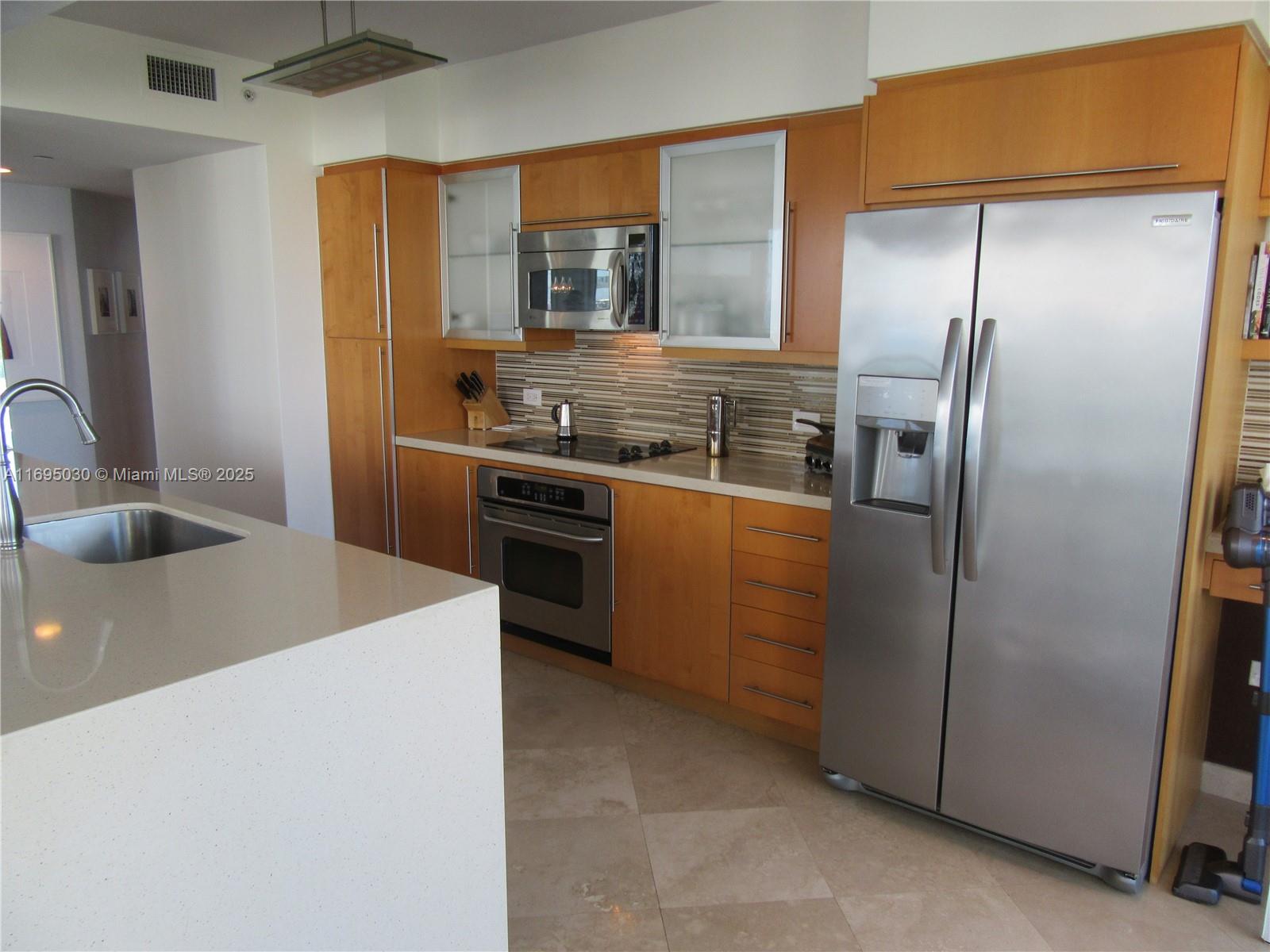 6365 Collins Avenue, Unit 1008 Miami Beach, FL 33141 - Photo 19 of 49 a kitchen with stainless steel appliances granite countertop a sink a stove and a refrigerator