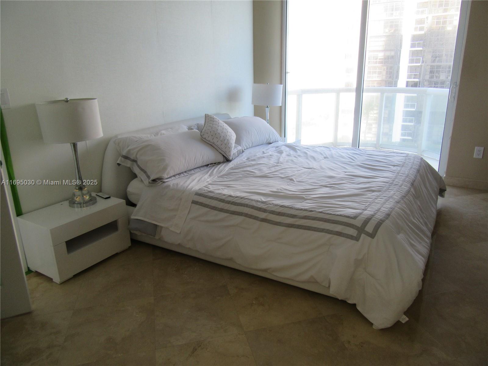 6365 Collins Avenue, Unit 1008 Miami Beach, FL 33141 - Photo 21 of 49 a bed sitting in a bedroom next to a window