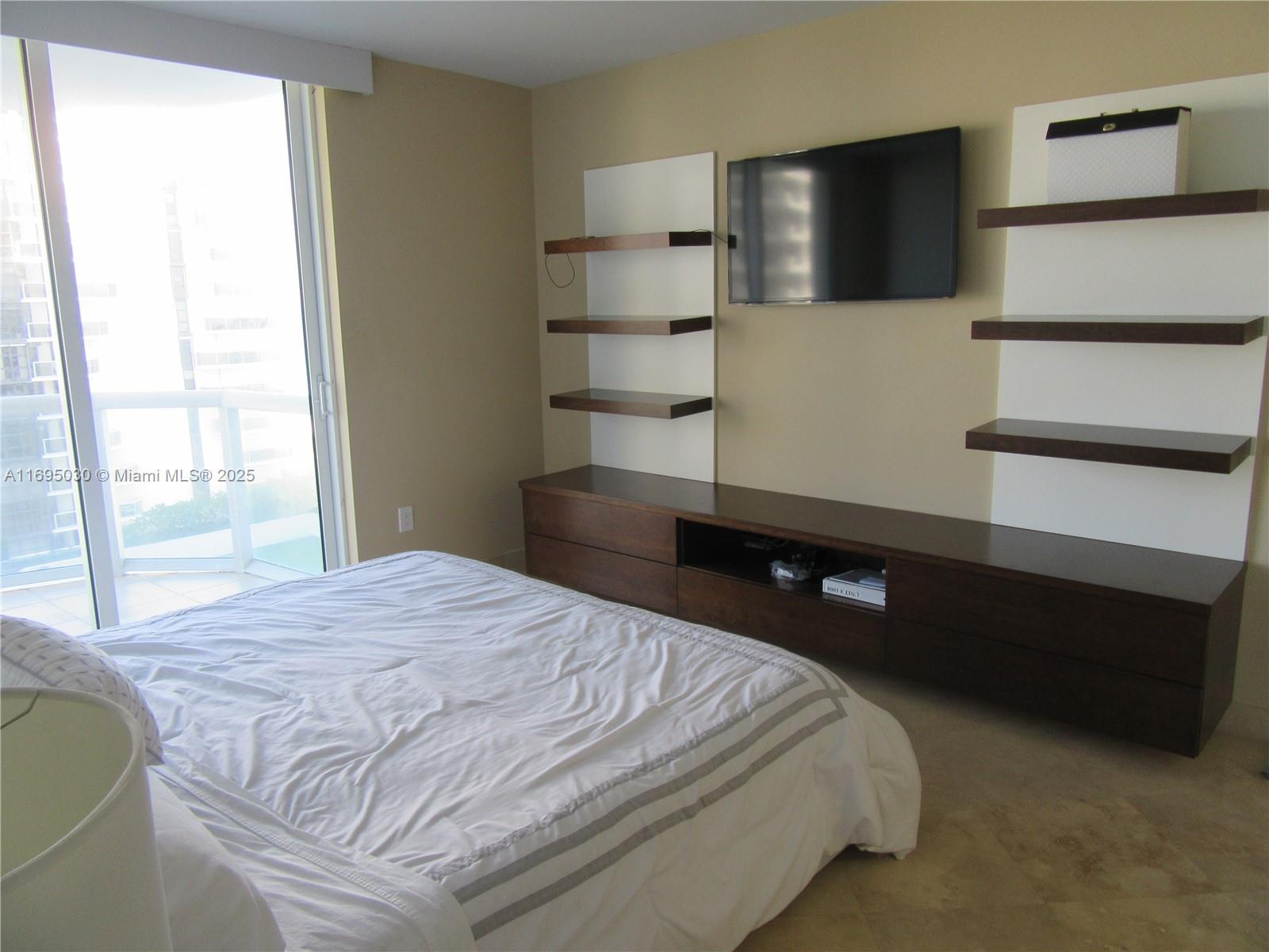 6365 Collins Avenue, Unit 1008 Miami Beach, FL 33141 - Photo 22 of 49 a bedroom with a bed and a television