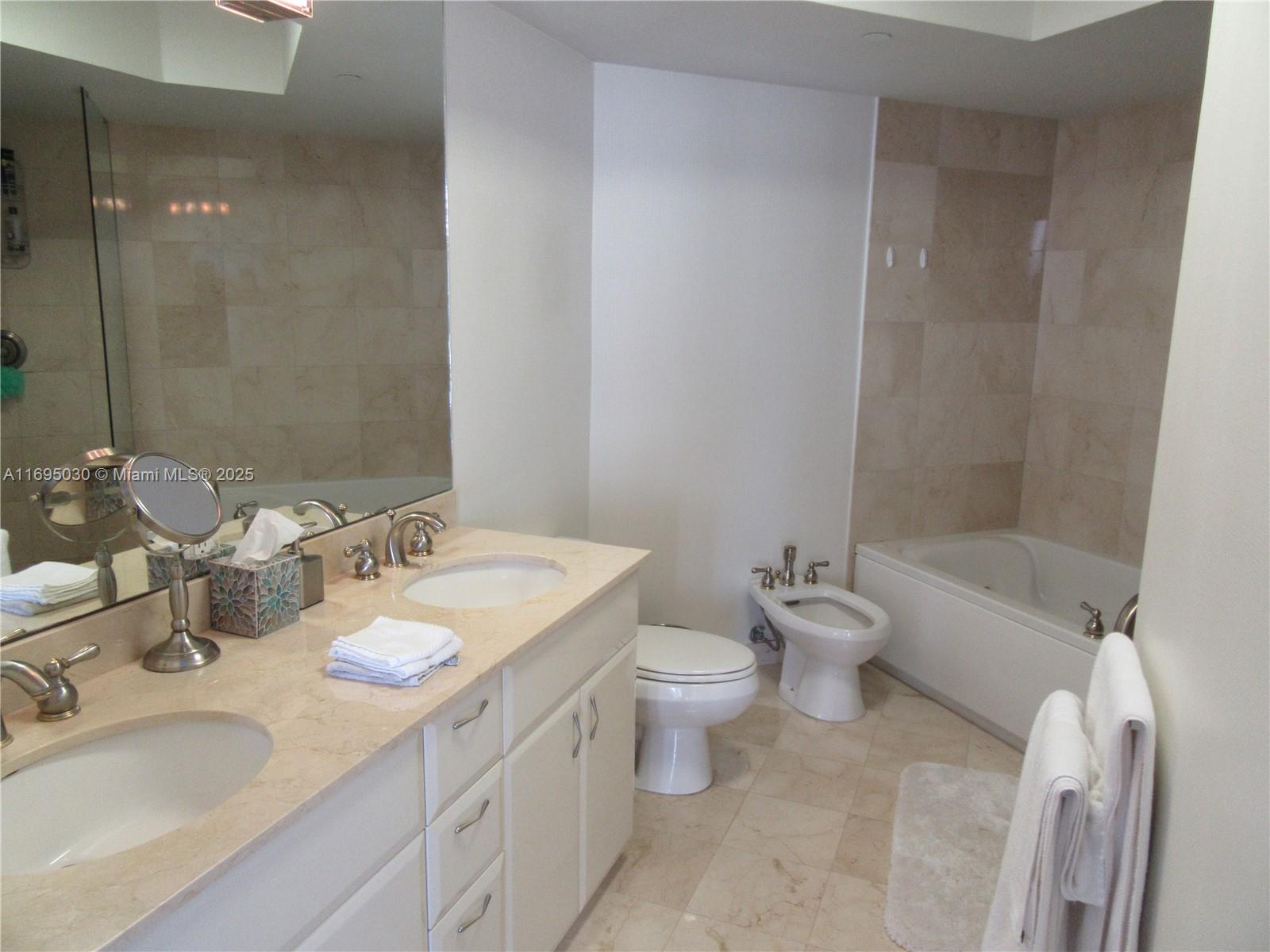 6365 Collins Avenue, Unit 1008 Miami Beach, FL 33141 - Photo 23 of 49 a bathroom with a granite countertop sink mirror toilet and bathtub