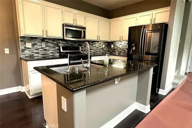 a kitchen with stainless steel appliances granite countertop a sink a microwave a refrigerator and a microwave