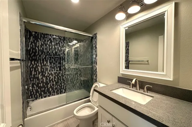 a bathroom with a granite countertop sink toilet mirror and shower