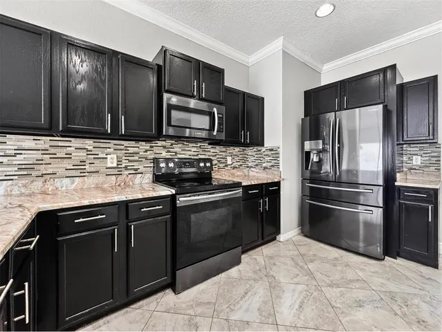 a kitchen with granite countertop a stove microwave and refrigerator