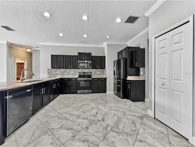 a kitchen with granite countertop a refrigerator and a stove top oven
