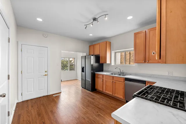 a kitchen with stainless steel appliances a refrigerator a sink dishwasher stove and oven with wooden floor