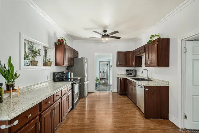 a large kitchen with stainless steel appliances granite countertop a stove top oven a sink dishwasher a dining table and chairs with wooden floor