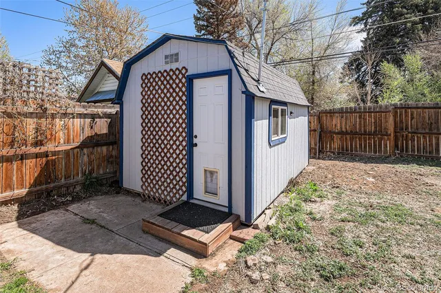 a view of a white house with a large trees and wooden fence