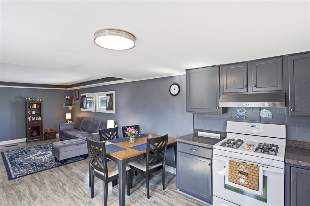 181 Boston Post Road East, Unit 34 Marlborough, MA 01752 - Photo 9 of 29 a kitchen with a stove a refrigerator and a dining table with wooden floor